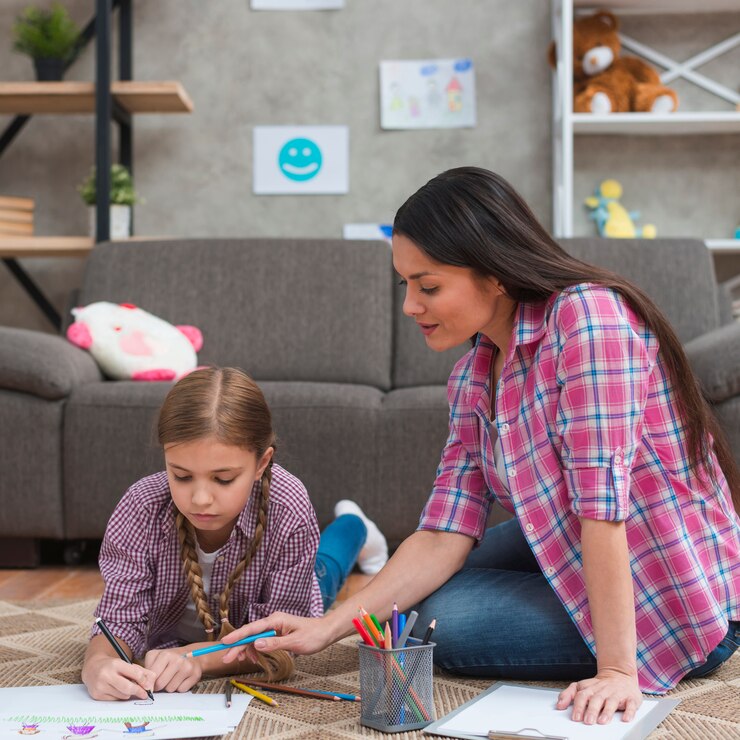 female-psychologist-helping-girl-draw-drawing-paper_23-2148026325