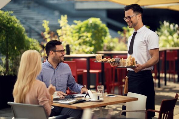 happy-waiter-serving-meal-couple-lunch-time-restaurant_637285-1922