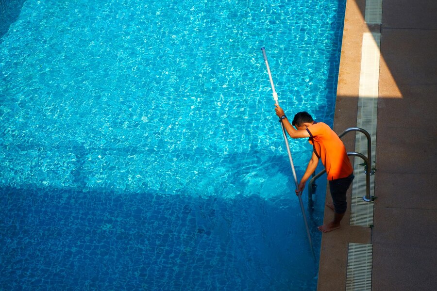 top-view-worker-cleaning-swimming-pool-private-house-summer_105751-15514